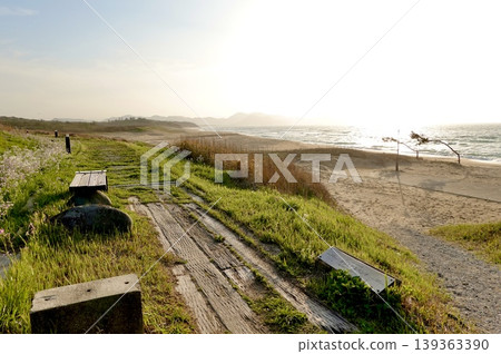 在京都府京丹後市阿野町濱爪夕日浦海灘的日落步道上,坐在沙灘上的長椅上欣賞日落。 在京都府京丹後市阿野町濱爪夕日浦海灘的日落步道上,坐在沙灘上的長椅上欣賞日落。 139363390