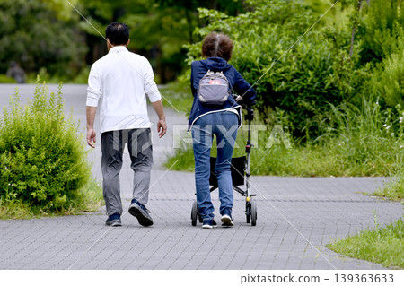 An elderly woman using a four-wheeled walker in the urban landscape of Yokohama, Japan... during the season of fresh greenery... = Yokohama City 139363633