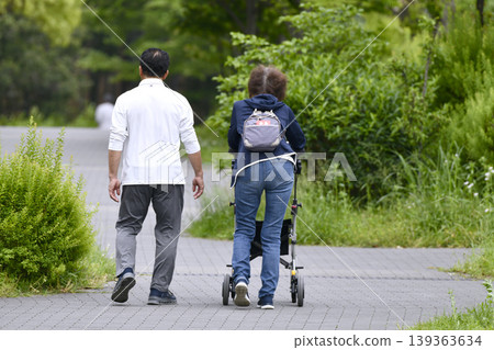 An elderly woman using a four-wheeled walker in the urban landscape of Yokohama, Japan... during the season of fresh greenery... = Yokohama City 139363634