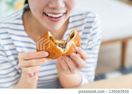 A young woman eating curry bread A young woman eating curry bread 139363930