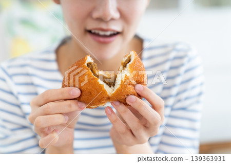 A young woman eating curry bread 139363931