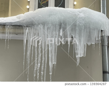 Icicles hanging from roof edge during winter season as frozen water forms unique shapes 139364287