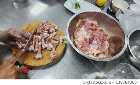 Chef deboning raw chicken meat on a wooden cutting board in a professional kitchen 139364360