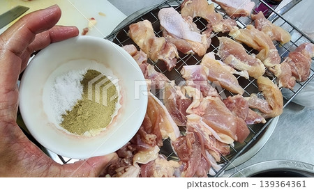 Chef Holding Bowl of Spice Blend over Raw Chicken for Marinating and Cooking 139364361