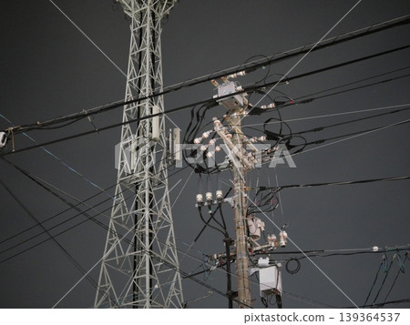 A landscape of utility poles and power lines stretching into the night sky A landscape of utility poles and power lines stretching into the night sky 139364537