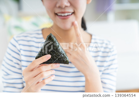 young woman eating rice balls 139364554