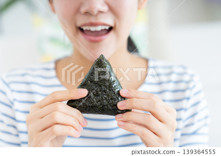 young woman eating rice balls 139364555