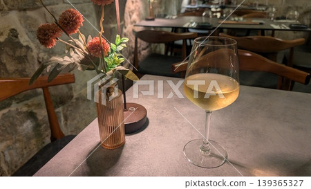 A glass of local white wine and pink dahlias in a vase 139365327