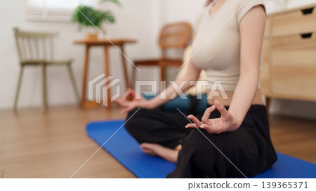 Asian women practice yoga meditation sitting lotus position on blue mat relax mindfulness wellness exercise routine healthy lifestyle workout training at home Asian women practice yoga meditation sitting lotus position on blue mat relax mindfulness wellness exercise routine healthy lifestyle workout training at home 139365371