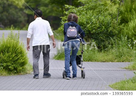 An elderly woman using a four-wheeled walker in the urban landscape of Yokohama, Japan... during the season of fresh greenery... = Yokohama City 139365593