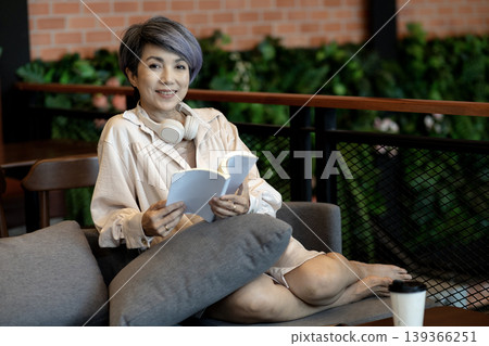 Asian adult woman reading book enjoying peaceful leisure time relaxed comfort modern cafe lounge cozy sofa Asian adult woman reading book enjoying peaceful leisure time relaxed comfort modern cafe lounge cozy sofa 139366251