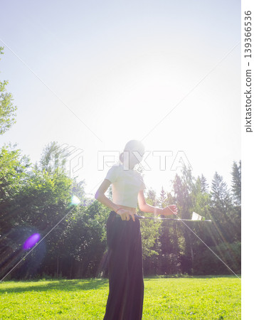 Teen girl playing badminton in summer park. Girl holding racket with shuttlecock outdoors. Active lifestyle and sport recreation concept. Sunny day in forest glade for outdoor activity. Teen girl playing badminton in summer park. Girl holding racket with shuttlecock outdoors. Active lifestyle and sport recreation concept. Sunny day in forest glade for outdoor activity. 139366536