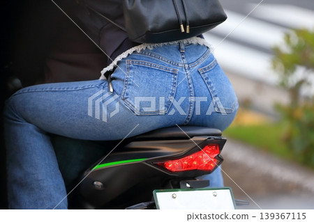 Image of a woman riding a motorcycle with another person. Image of a woman riding a motorcycle with another person. 139367115