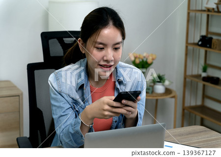 Asian woman adult using smartphone laptop home office desk remote work digital communication online business modern workspace connection lifestyle Asian woman adult using smartphone laptop home office desk remote work digital communication online business modern workspace connection lifestyle 139367127