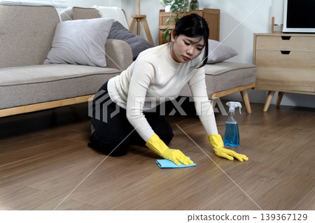 Asian adult woman house cleaning expert diligently scrubbing wooden floor modern living room home 139367129