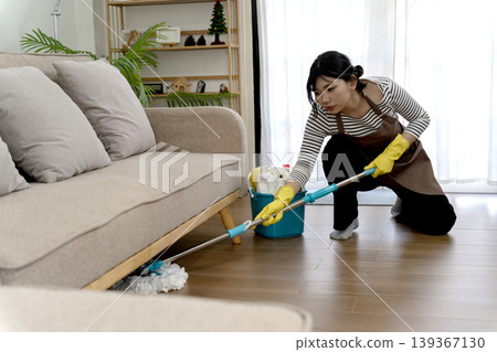 Asian adult woman cleaning living room floor diligent housekeeper doing domestic chores home maintenance tasks Asian adult woman cleaning living room floor diligent housekeeper doing domestic chores home maintenance tasks 139367130