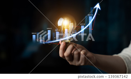 Creative hand holding glowing light bulb with growing graph, representing innovation, ideas, and business success in a digital era Scalp 139367142