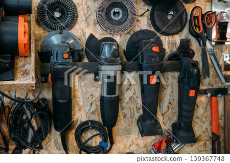 Tool storage. Workshop wall set. Electric angle grinder discs hanging on metal rack with professional handheld power equipment in carpentry. Tool storage. Workshop wall set. Electric angle grinder discs hanging on metal rack with professional handheld power equipment in carpentry. 139367748