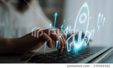 A close-up of hands typing on a laptop with a futuristic rocket graphic and upward arrows, symbolizing growth and success in digital marketing and business strategies. Sigmoid A close-up of hands typing on a laptop with a futuristic rocket graphic and upward arrows, symbolizing growth and success in digital marketing and business strategies. Sigmoid 139368162