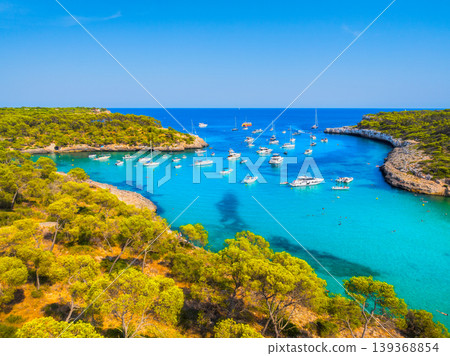 Aerial view of luxury yachts and boats anchored in a turquoise bay on the coast of Mallorca, Spain. Aerial view of luxury yachts and boats anchored in a turquoise bay on the coast of Mallorca, Spain. 139368854