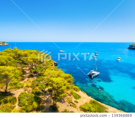 Aerial view of luxury yachts and boats anchored in a turquoise bay on the coast of Mallorca, Spain. Aerial view of luxury yachts and boats anchored in a turquoise bay on the coast of Mallorca, Spain. 139368869
