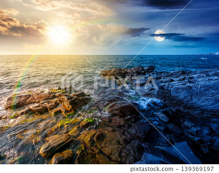 day meet night. sea coast with stones and boulders. view of beach with rock in seaweed. sun and moon on epic sky above horizon. autumn equinox harmony concept for astrology background day meet night. sea coast with stones and boulders. view of beach with rock in seaweed. sun and moon on epic sky above horizon. autumn equinox harmony concept for astrology background 139369197