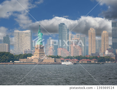 New york, usa august 16,2024. Iconic statue of liberty rising over liberty island with manhattan skyline and harbor under a bright blue summer sky, wide view New york, usa august 16,2024. Iconic statue of liberty rising over liberty island with manhattan skyline and harbor under a bright blue summer sky, wide view 139369514