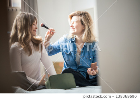Mother applying makeup to young woman bonding indoors 139369690