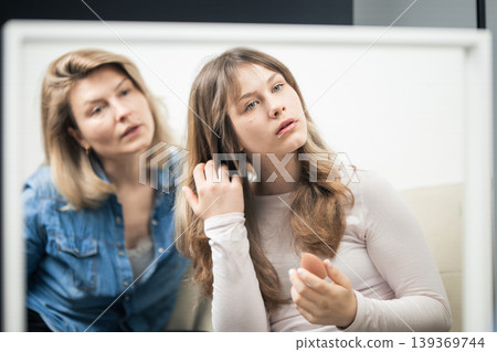Teen girl learning makeup from mother reflecting in mirror 139369744