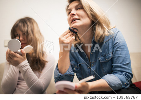 Women applying makeup, sharing beauty routine together 139369767