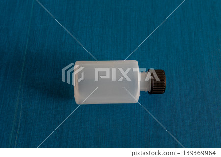 White plastic bottle with black cap on blue background White plastic bottle with black cap on blue background 139369964