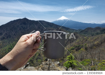 Drinking coffee while gazing at Mount Fuji at the summit. An image of a break during a mountain climb. Drinking coffee while gazing at Mount Fuji at the summit. An image of a break during a mountain climb. 139369984