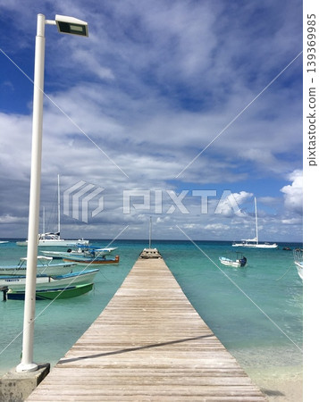 Wooden pier leading to tropical turquoise sea with boats under dramatic clouds sky, travel destination background Wooden pier leading to tropical turquoise sea with boats under dramatic clouds sky, travel destination background 139369985