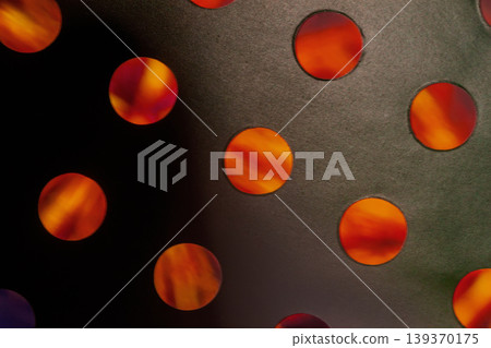 Orange light shines through circular holes in perforated metal surface, orange light pattern for design. Natural background, abstract pattern, contrast, modern design, copy space Orange light shines through circular holes in perforated metal surface, orange light pattern for design. Natural background, abstract pattern, contrast, modern design, copy space 139370175