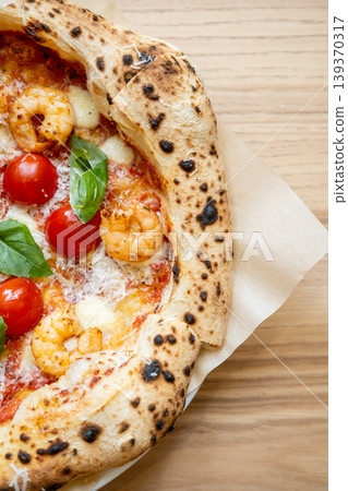 Italian pizza. Homemade dish. Fresh food with tomatoes melted cheese mozzarella shrimp green basil leaves with sauce on wooden table. Italian pizza. Homemade dish. Fresh food with tomatoes melted cheese mozzarella shrimp green basil leaves with sauce on wooden table. 139370317