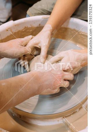 Art education. Creative learning. Unrecognizable woman master hands teaching girls pottery ceramic in class using electric professional wheel. Art education. Creative learning. Unrecognizable woman master hands teaching girls pottery ceramic in class using electric professional wheel. 139370324
