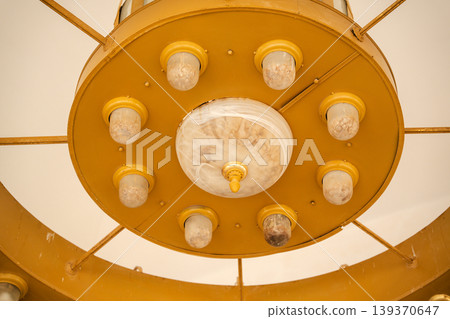 Close up view of mosque chandelier central disk with marble glass diffuser and multiple small lamps arranged in circular metal frame. Islamic religion, architecture, interior lighting 139370647