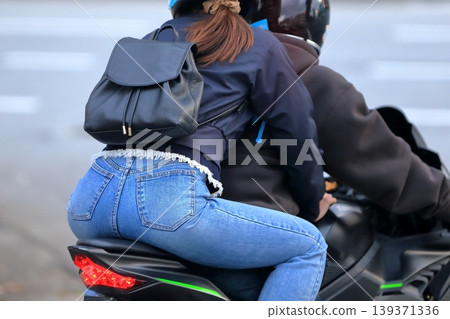 Image of a woman riding a motorcycle with another person. Image of a woman riding a motorcycle with another person. 139371336