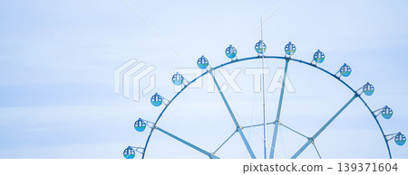 A simple, faintly cloudy background with an imaginative landscape featuring a Ferris wheel. 139371604