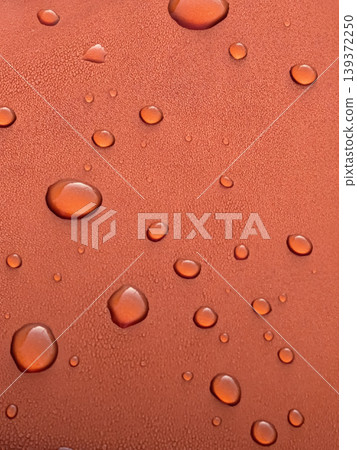 Close-up of water droplets floating on an orange water-repellent surface / Texture background material that conveys a sense of waterproofing and cleanliness. Close-up of water droplets floating on an orange water-repellent surface / Texture background material that conveys a sense of waterproofing and cleanliness. 139372250