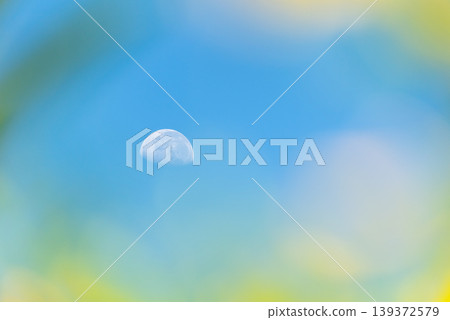 Half moon visible in clear blue sky with soft blurred edges creating dreamy frame minimal composition calm atmosphere natural light peaceful space background 139372579