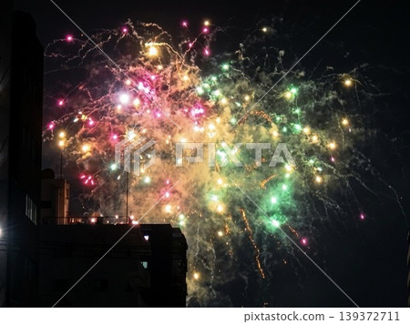 Colorful and vibrant fireworks light up the city night sky. Colorful and vibrant fireworks light up the city night sky. 139372711