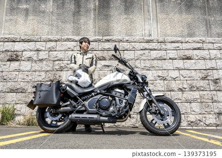 A white cruiser bike and a standing male rider. 139373195