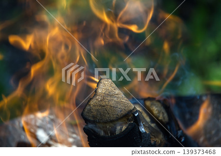 Close-Up Of A Burning Wood Log With Dancing Flames And Smoke In An Outdoor Campfire 139373468