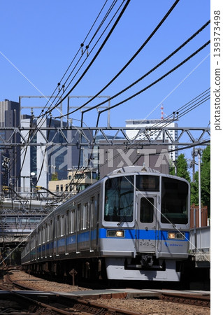 Odakyu Line 2000 series train running with the cluster of buildings near Shinjuku in the background. Odakyu Line 2000 series train running with the cluster of buildings near Shinjuku in the background. 139373498