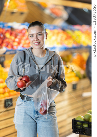 Young woman choosing apples in vegetable shop Young woman choosing apples in vegetable shop 139373550