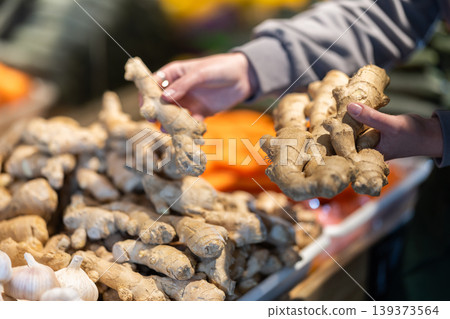 Female seller's hands placing ginger on store counter Female seller's hands placing ginger on store counter 139373564