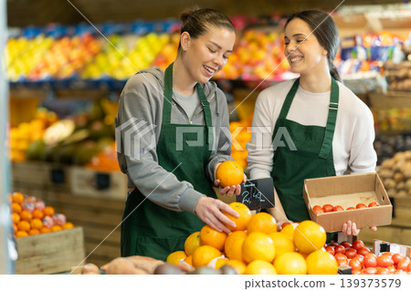 Two sellers place oranges and tomatoes on store counter Two sellers place oranges and tomatoes on store counter 139373579