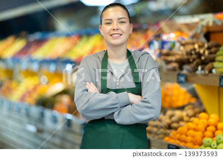 Young female shop assistant inviting in vegetable store Young female shop assistant inviting in vegetable store 139373593