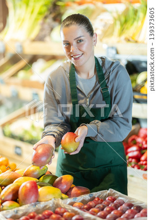 While working in supermarket, employee forms display case, puts ripe mango in pile While working in supermarket, employee forms display case, puts ripe mango in pile 139373605